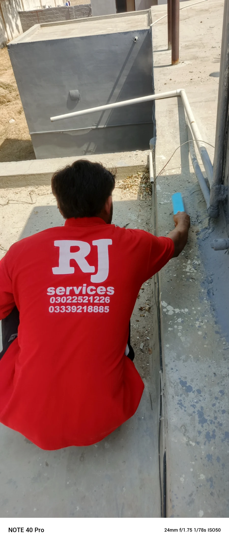RJ Services technician preparing an exterior surface beside a roof edge